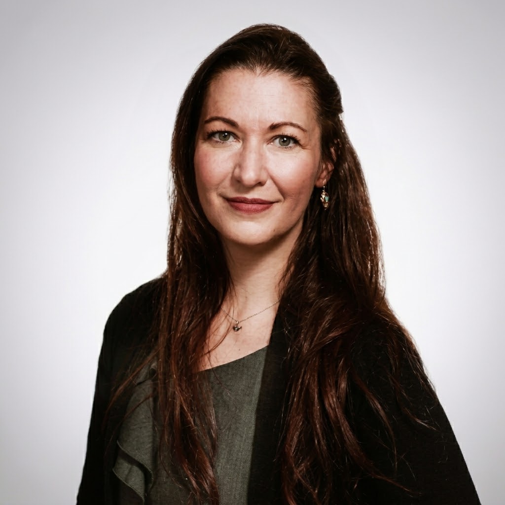 A woman with long dark hair smiles at the camera.