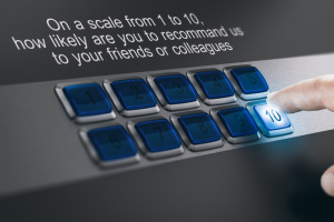 A hand presses the 10 button on a keypad below a survey question asking, On a scale from 1 to 10, how likely are you to recommend us to your friends or colleagues?.